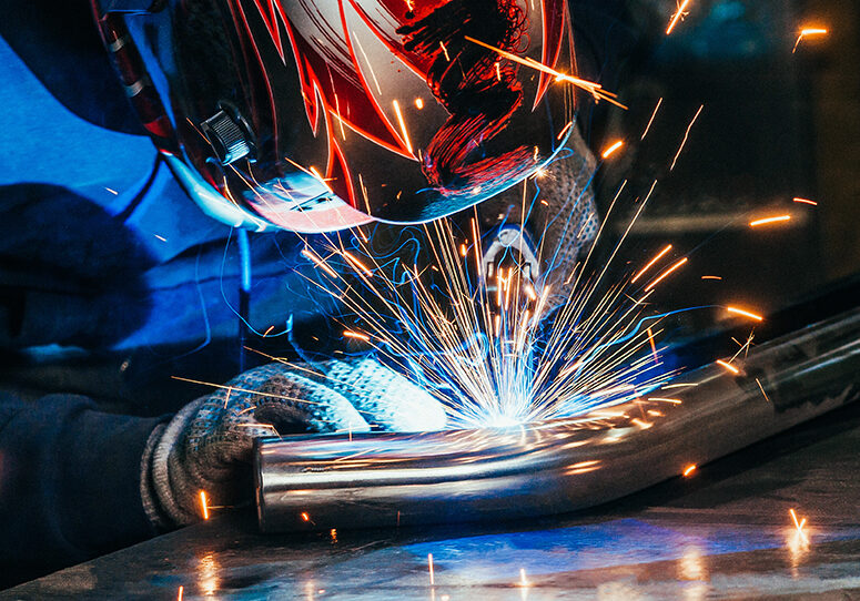 Welder in mask welding metal and sparks metal. Toned image.