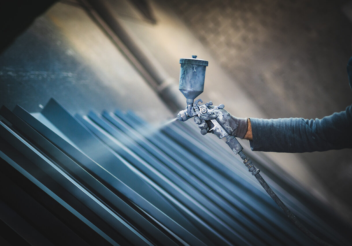 Man painting metal products with a spray gun