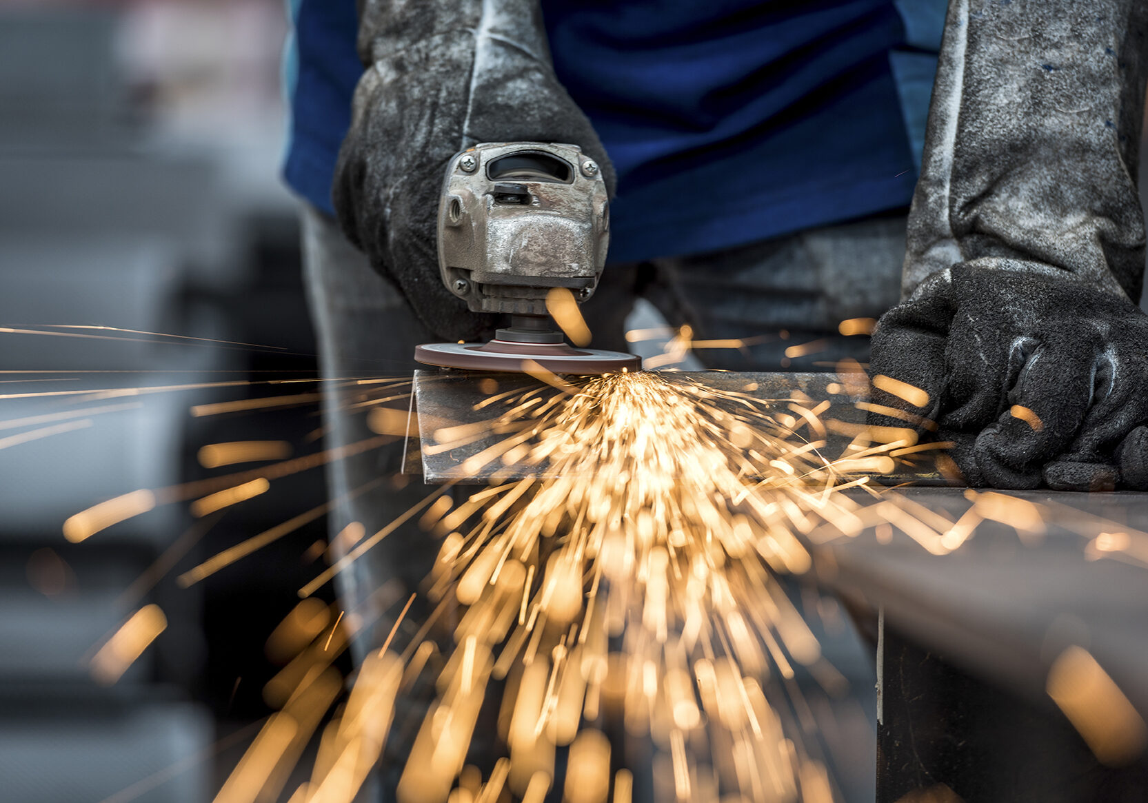 Industrial worker cutting metal with many sharp sparks